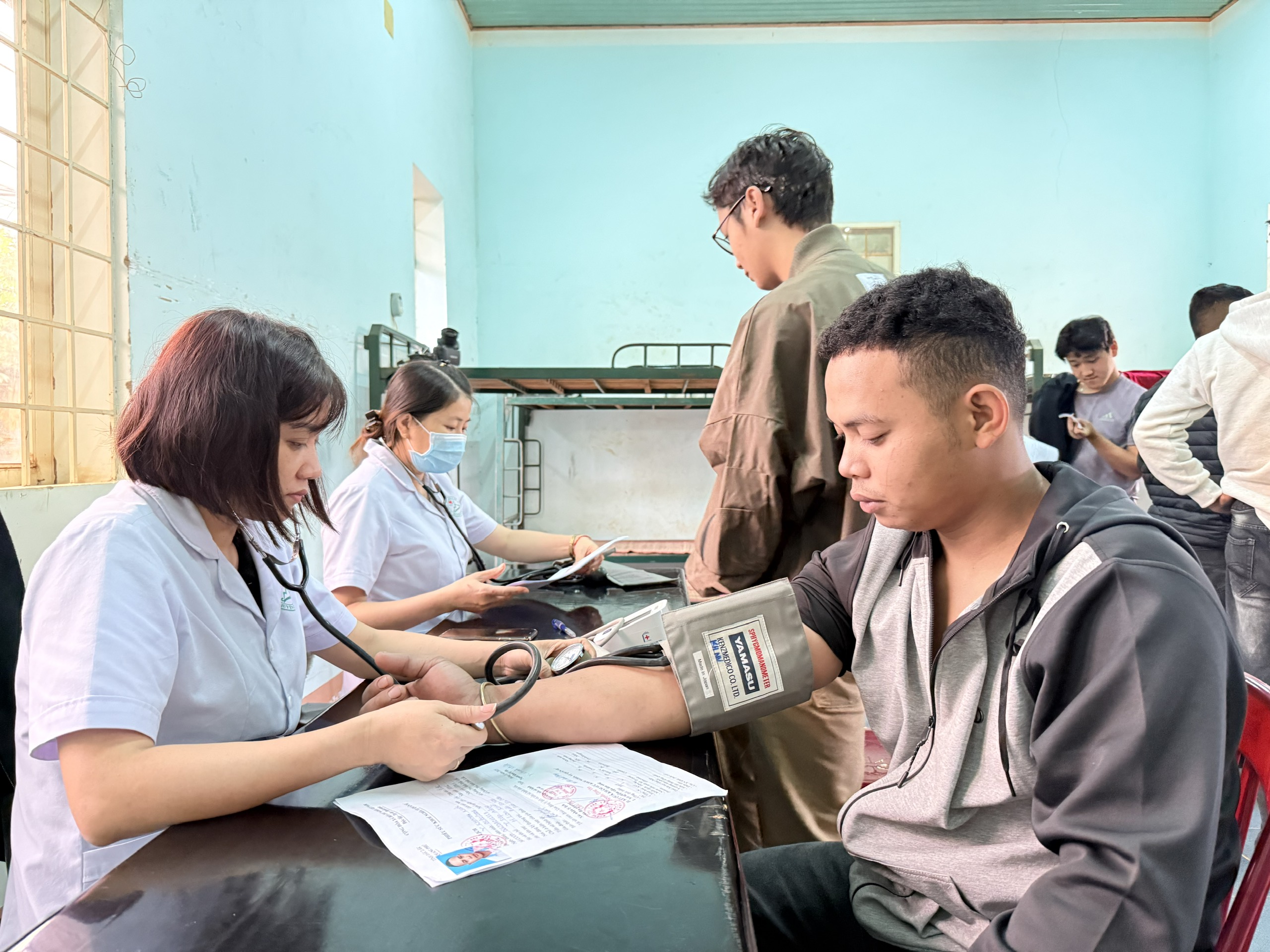 Cán bộ y tế đo huyết áp cho thanh niên tham gia NVQS